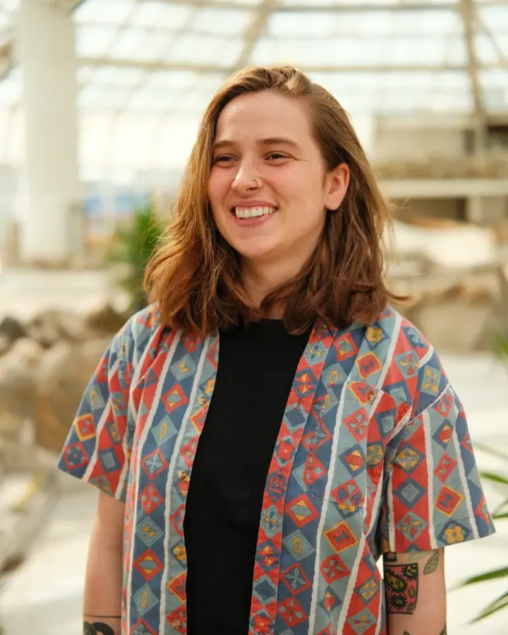 Zuzanna Zielinska sorride in una serra, con una camicia a motivi colorati